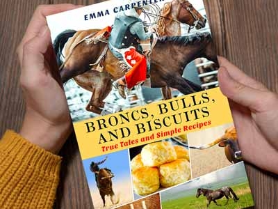 A pair of hands holding the book "Broncs, Bulls, and Biscuits"